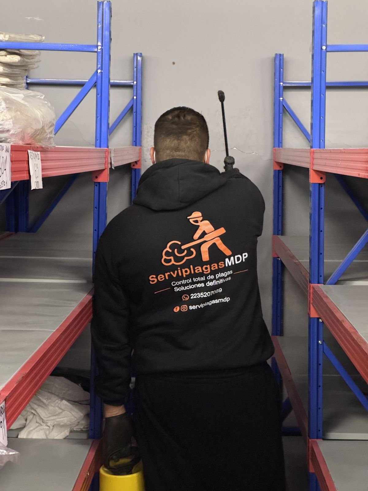 Técnico de ServiplagasMDP aplicando producto en estanterías de un depósito